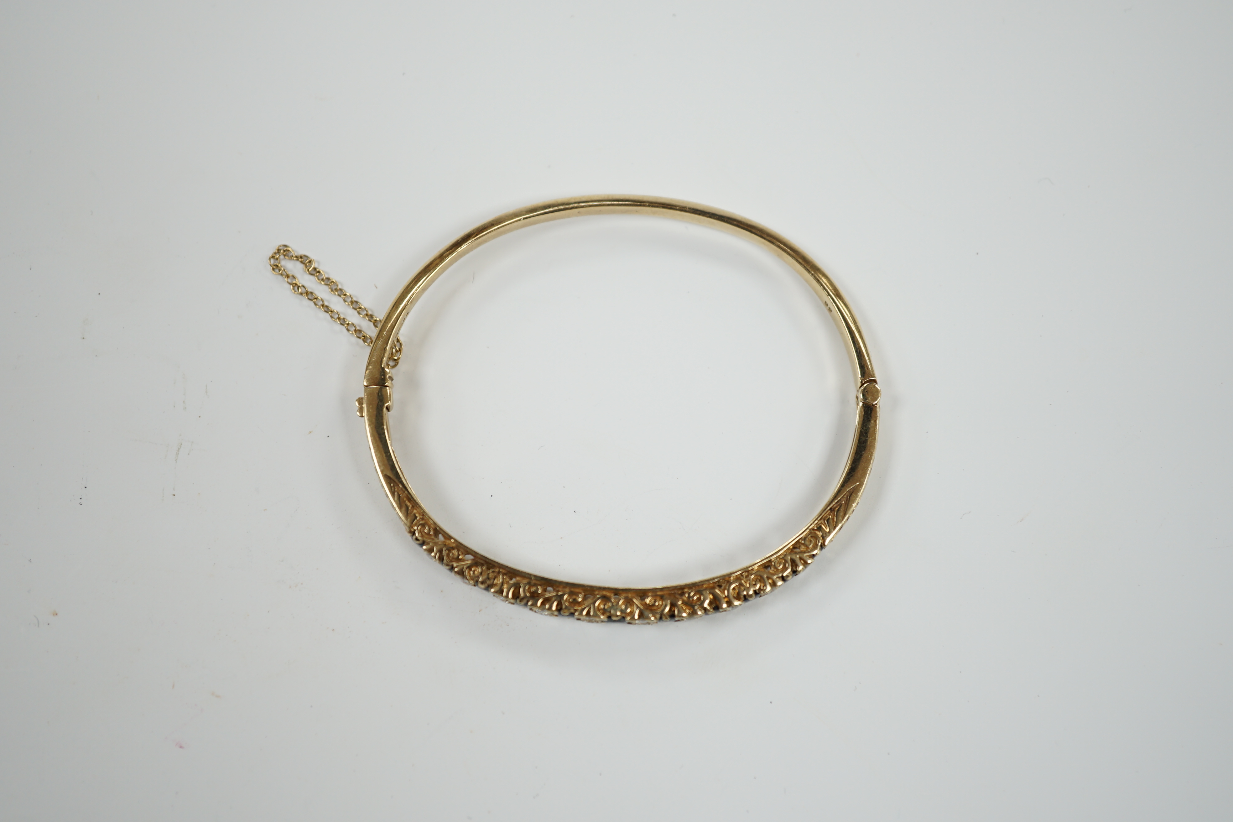 A modern 9ct gold, sapphire and diamond cluster set hinged bangle, gross weight 14 grams.